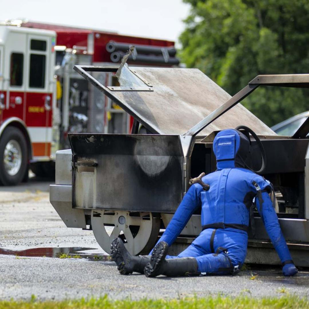 LION® SmartDummy™ Extrication sitting next to a training vehicle with a fire truck in the background
