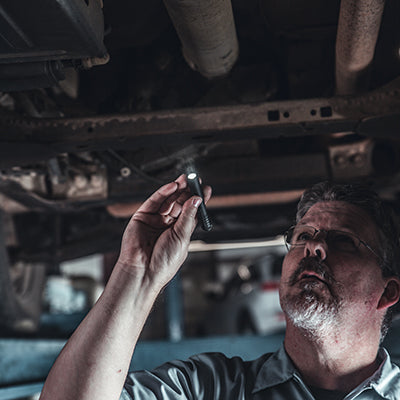 Mechanic using a Streamlight MicroStream® USB Pocket Light under a car